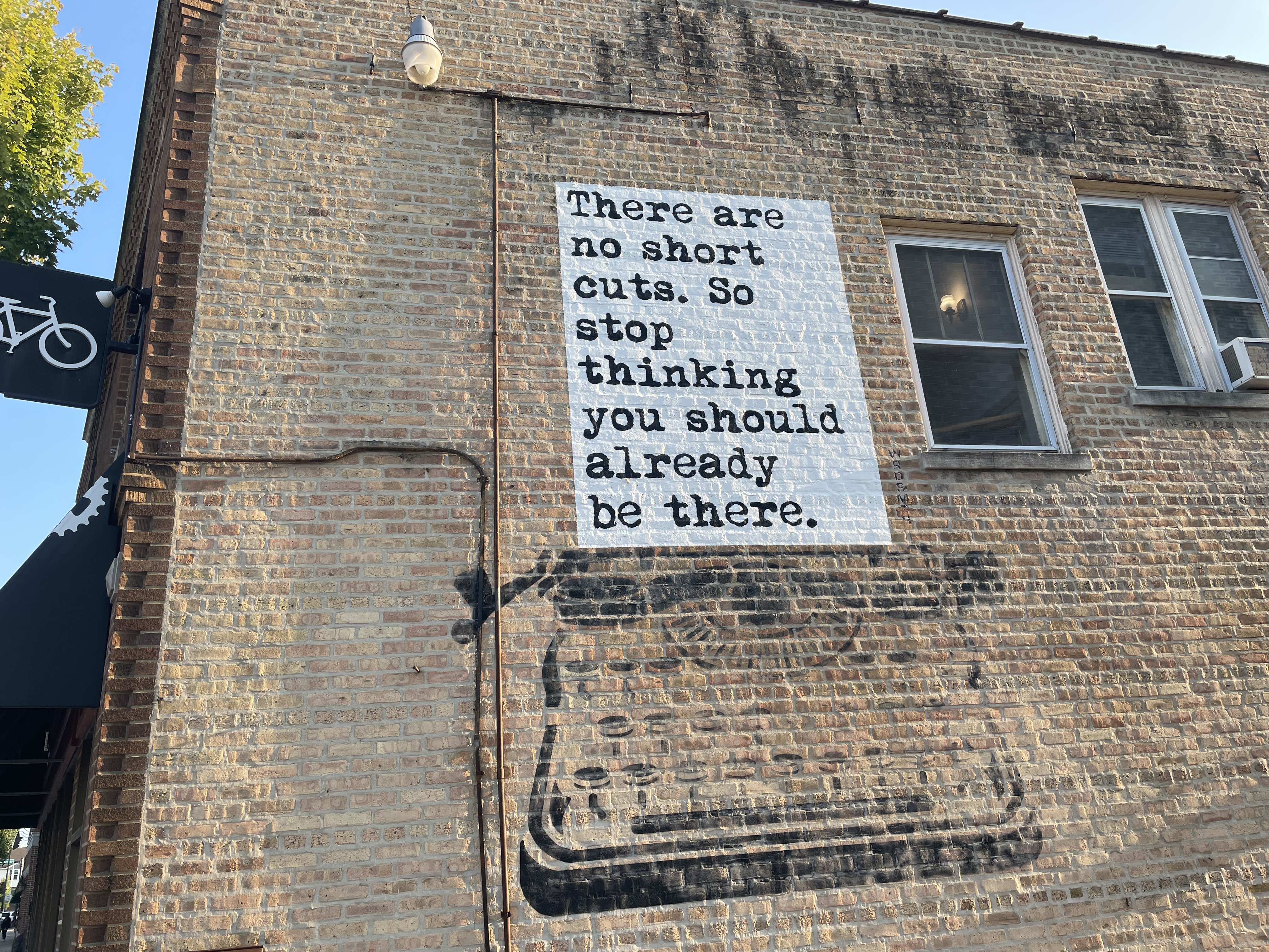 Picture of a wall on a side of a building that reads: 'There are no shortcuts. So stop thinking you should already be there.' 